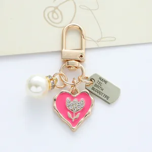 Detailed view of pink heart keychain with rhinestone flower, pearl and id tag charm