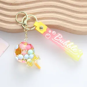 Detail of cute lollipop quicksand keychain with pink and yellow gradient strap