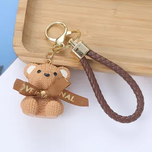 Close-up of resin teddy bear keychain with knitted texture and braided cord