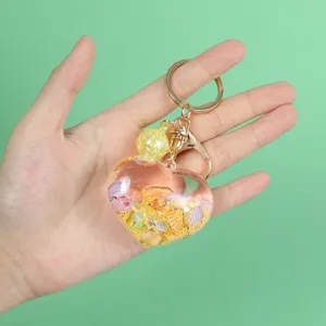 Detailed view of heart liquid keychain with shells and yellow glitter sand