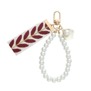 Elegant pearl keychain with leaf print ribbon and gold alloy clasp for bags or car keys.