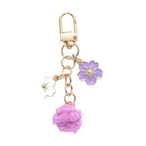 Purple cherry blossom keychain with soft pom-pom and gold lobster clasp for bags.