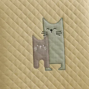 Détail du tissu de coussin matelassé avec des chats brodés mignons, texture douce.