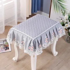 Detailed view of grey quilted square stool cover with elegant lace floral embroidery trim.