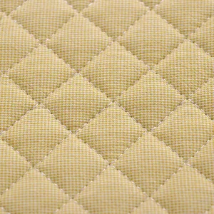 Gros plan sur le tissu matelassé losange jaune pour détail de coussin de chaise, textile doux.