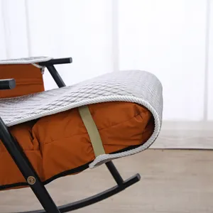 Close-up detail of grey quilted rocking chair cushion with orange base and white braided edge.
