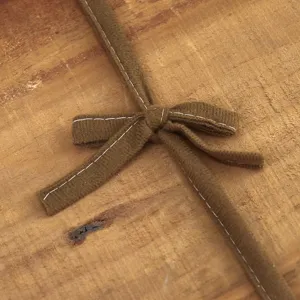 Primo piano dettaglio del cinturino della copertura dello sgabello in tessuto marrone.