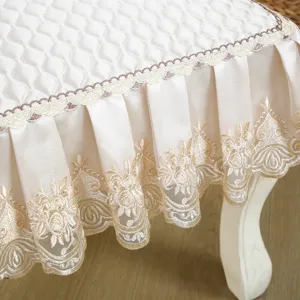 Close-up of European quilted chair cover with elegant embroidered lace pleated skirt in beige.