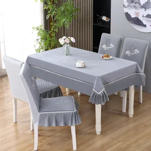 Conjunto de mantel de comedor acolchado gris y fundas para sillas con detalle de bordado.