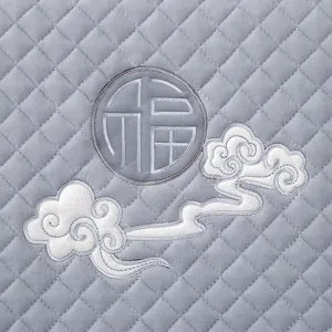 Detalle de funda para silla de comedor acolchada gris con un elegante bordado tradicional.