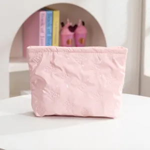 Vista detallada de un neceser rosa acolchado con motivos de lazos grabados en relieve
