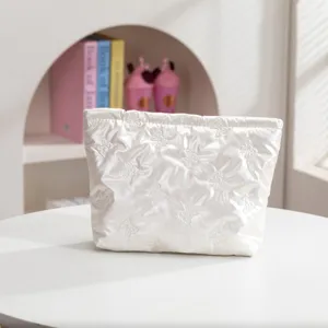 Vista detallada que muestra la suave textura acolchada y los bordados del neceser