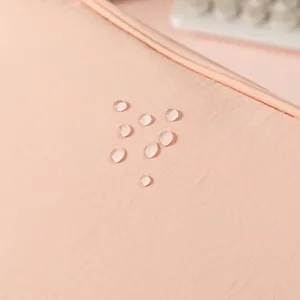 Close-up of waterproof pink fabric detail with water droplets for travel makeup bag