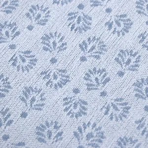 Gros plan sur la texture du tissu bleu clair à motif floral d'un coussin de chaise.