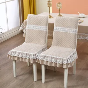 Beige quilted chair covers with white lace trim and ruffles on dining chairs