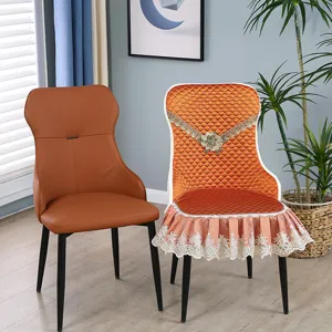 Close-up of orange quilted dining chair cover with floral embroidery and lace skirt detail
