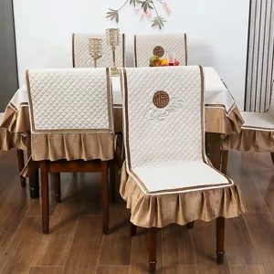 Detailansicht gesteppter beiger Stuhlhussen mit braunen Rüschen und traditioneller Stickerei