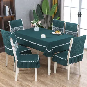 Détail d'une nappe nordique vert foncé et de housses de chaise à volants en dentelle.