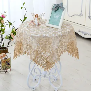 Detailed view of vintage gold lace round tablecloth, decorative floral embroidery design.