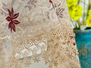 Primer plano de exquisito mantel de encaje beige con elegante bordado floral rojo y borde.