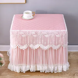Fodera antipolvere rosa con ricamo in pizzo bianco per comodino o tavolino da casa elegante.