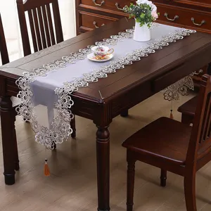 Elegante runner da tavola in pizzo bianco ricamato con nappe, perfetto per sala da pranzo.