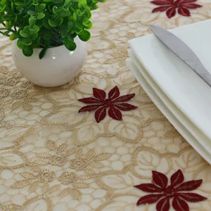 Primer plano detallado de mantel bordado en encaje con diseño floral rojo y elegante malla.