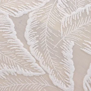 Detalle de mantel de encaje blanco con exquisito bordado de hojas para decoracion de mesa.