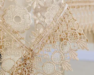 Gold lace embroidered hollow tablecloth detail, exquisite mesh fabric for home decor.