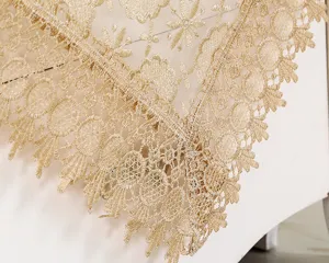 Close-up detail of luxury golden lace embroidered tablecloth, exquisite floral pattern edge.