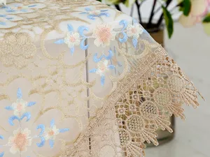 Detailed view of elegant lace embroidered tablecloth with gold and floral patterns.