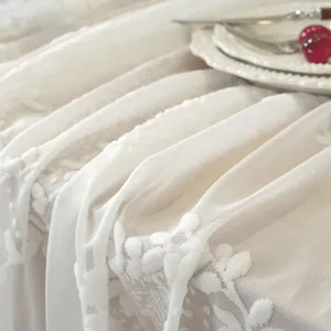 Primo piano di un runner da tavola in pizzo bianco con elegante ricamo floreale per decorazione.