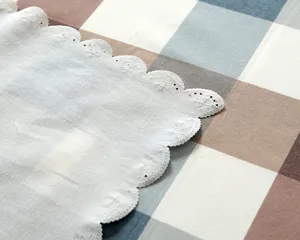 Nappe blanche en dentelle avec bordure festonnée et broderie délicate pour table.