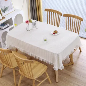 Detalle de mantel de encaje blanco con volantes de malla delicados y escena de comedor elegante.