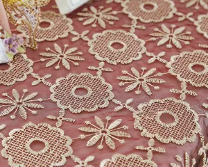 Detailed close-up of gold embroidered mesh tablecloth fabric, elegant floral pattern.
