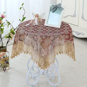 Detailed view of elegant red lace round tablecloth with gold floral embroidery and fringe trim.
