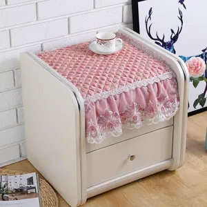Pink quilted nightstand dust cover with delicate lace ruffled edge for bedroom decor.