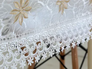 Primer plano de un elegante mantel de encaje blanco con detalles de bordado floral.