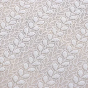 Primer plano de tela de encaje blanco con elegante patrón de hojas y textura suave.
