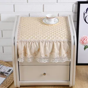 Detailed view of beige quilted bedside table dust cover with elegant lace trim and embroidery.