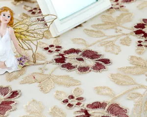 Close-up of exquisite lace embroidered tablecloth with gold and red floral details.