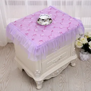 Elegante funda de encaje púrpura para mesita de noche con bordado floral y volantes.