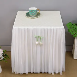 Copertura antipolvere trapuntata per comodino con elegante gonna in rete bianca e fiocco di tulipano.