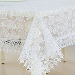 White lace tablecloth detail shot, delicate floral embroidered mesh design for elegant home decor.