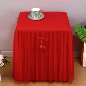 Copertura antipolvere rossa per comodino con gonna in tulle e fiocco decorativo elegante.