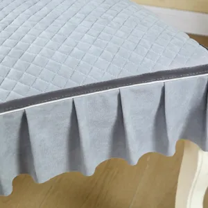 Close-up detail of light blue quilted dining chair cover with elegant pleated skirt and trim.
