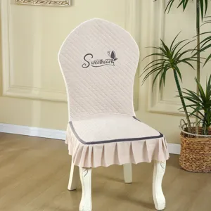 Beige quilted dining chair cover with elegant ruffles and sweethearts embroidery, detail view.