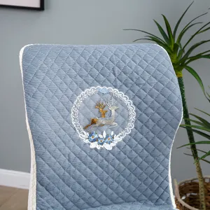 Détail de housse de chaise matelassée bleue, motif de cerf brodé élégant avec bordure en dentelle.