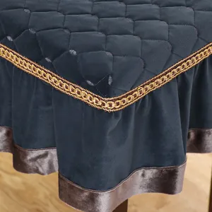 Close-up detail of square stool cover with quilted velvet top and golden braided trim.