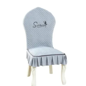 Elegant quilted dining chair cover with ruffles, soft light blue slipcover for home decor.